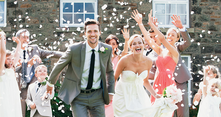 Newlyweds smile as they leave wedding and confetti rains down on them